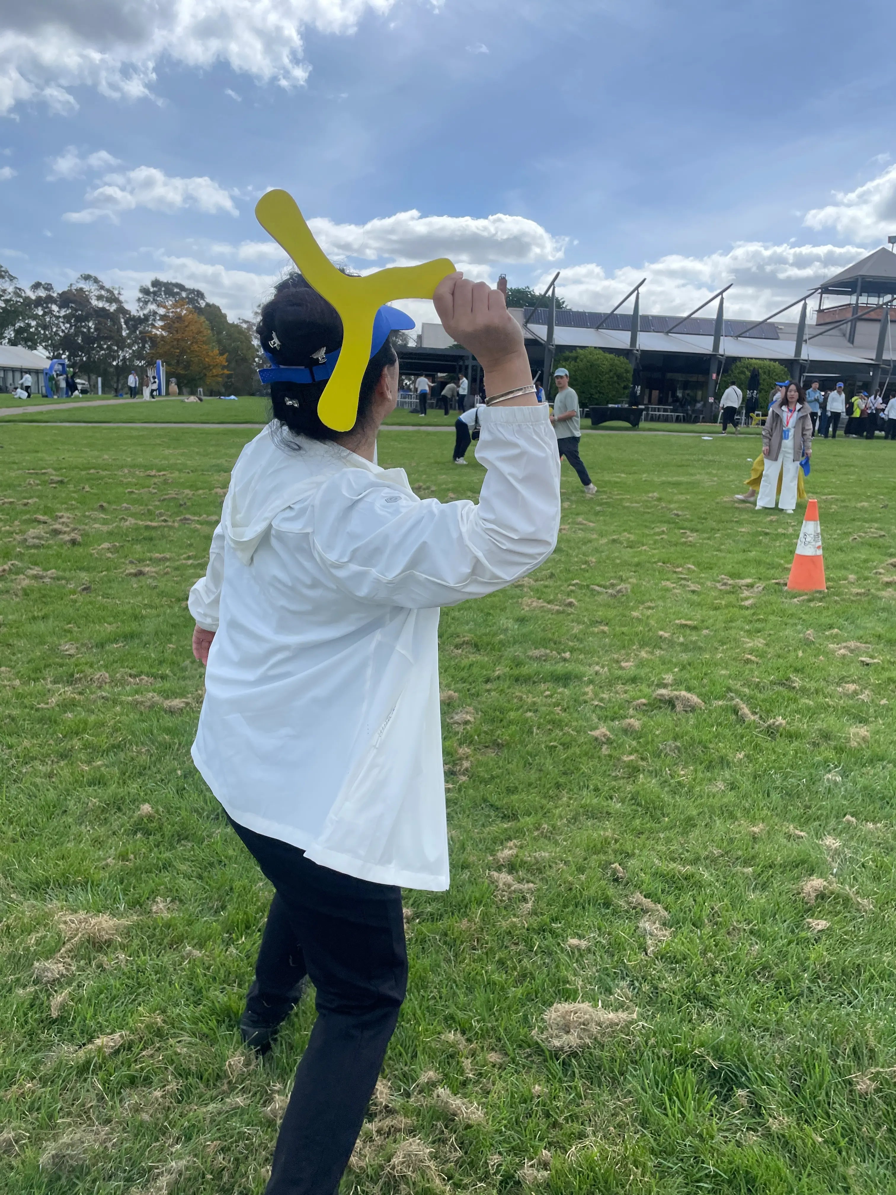 Woman throwing a FlyingToyz yellow OZzie Icerunner foam boomerang at an outdoor community event in Australia