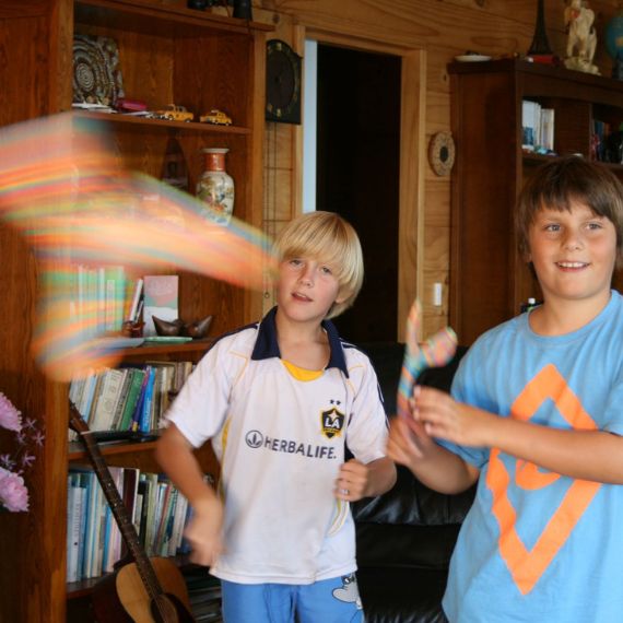 Two children playing with colorful indoor superangs in a room with bookshelves and decor.