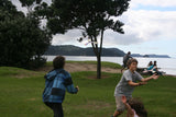 Children playing with superang boomerangs in a park by the sea